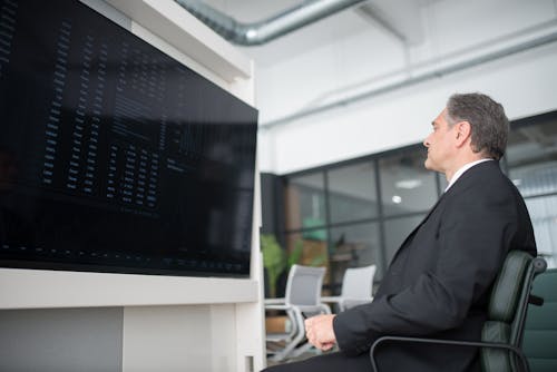 Free Man Sitting on Office Chair While Looking at Screen of a Monitor Stock Photo