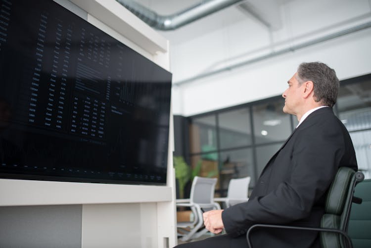 Man Sitting On Office Chair While Looking At Screen Of A Monitor