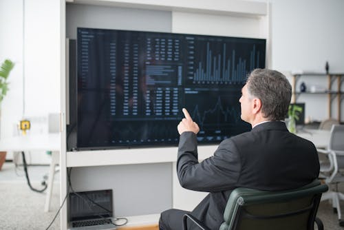 Man in Black Suit Jacket Sitting on Chair While Pointing His Finger