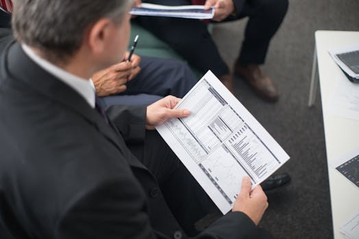 Two businessmen analyze financial documents during a meeting, focusing on data trends and performance.
