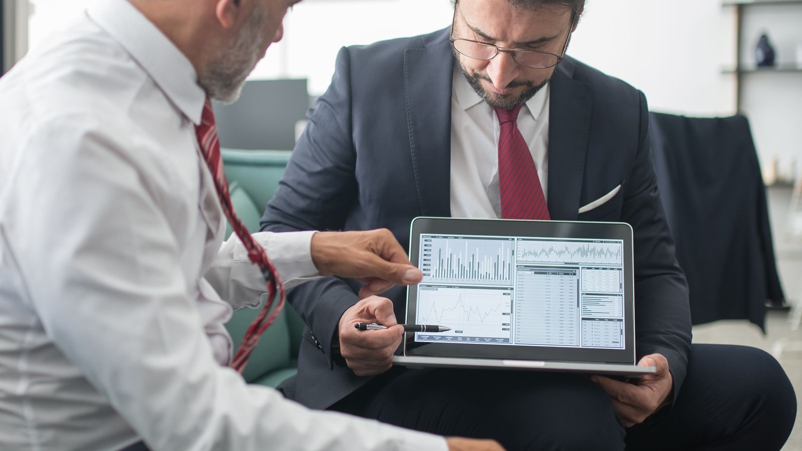 Two professionals reviewing technical data on a laptop during a sales meeting