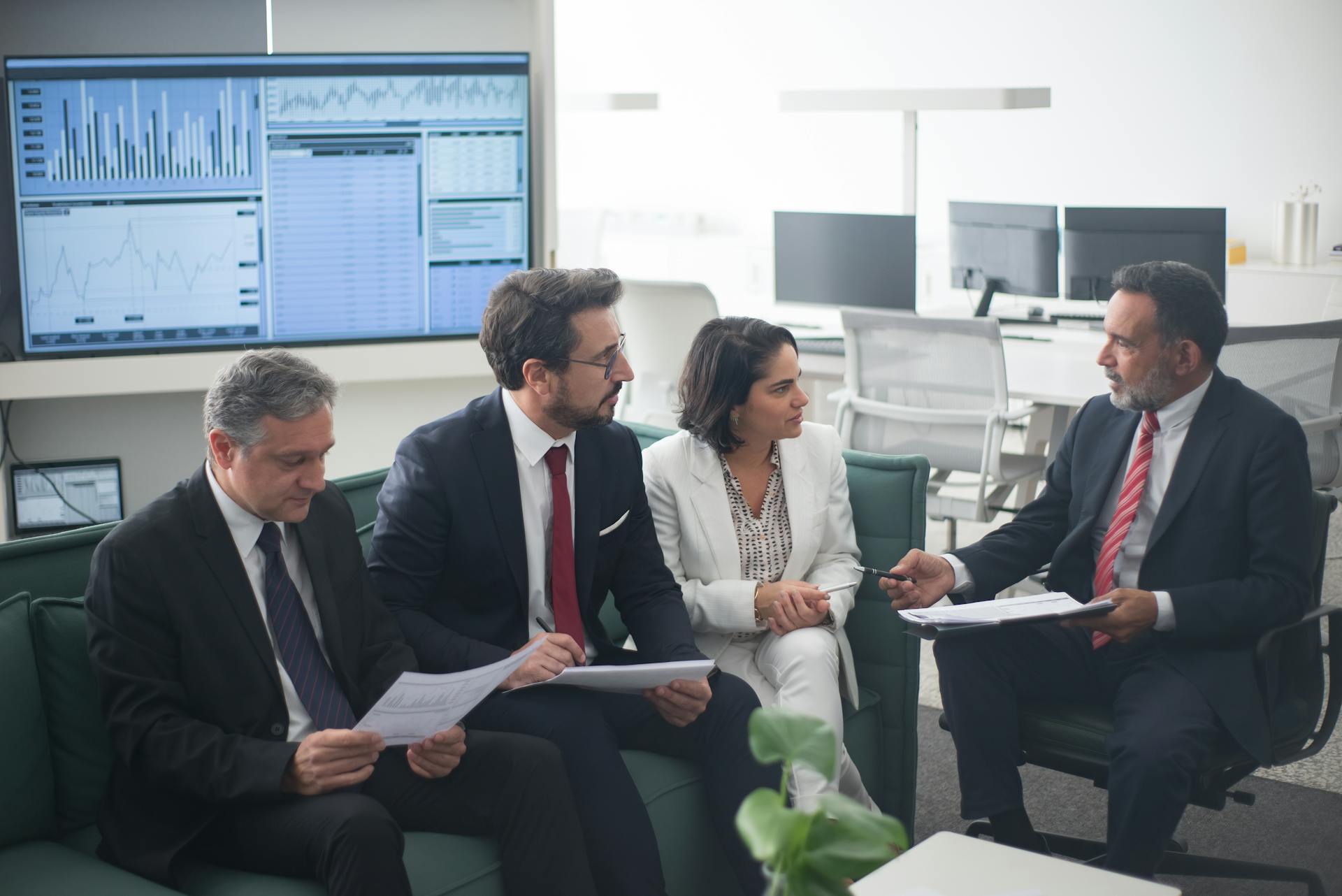 Group of business professionals discussing financial strategies in a modern office setting.