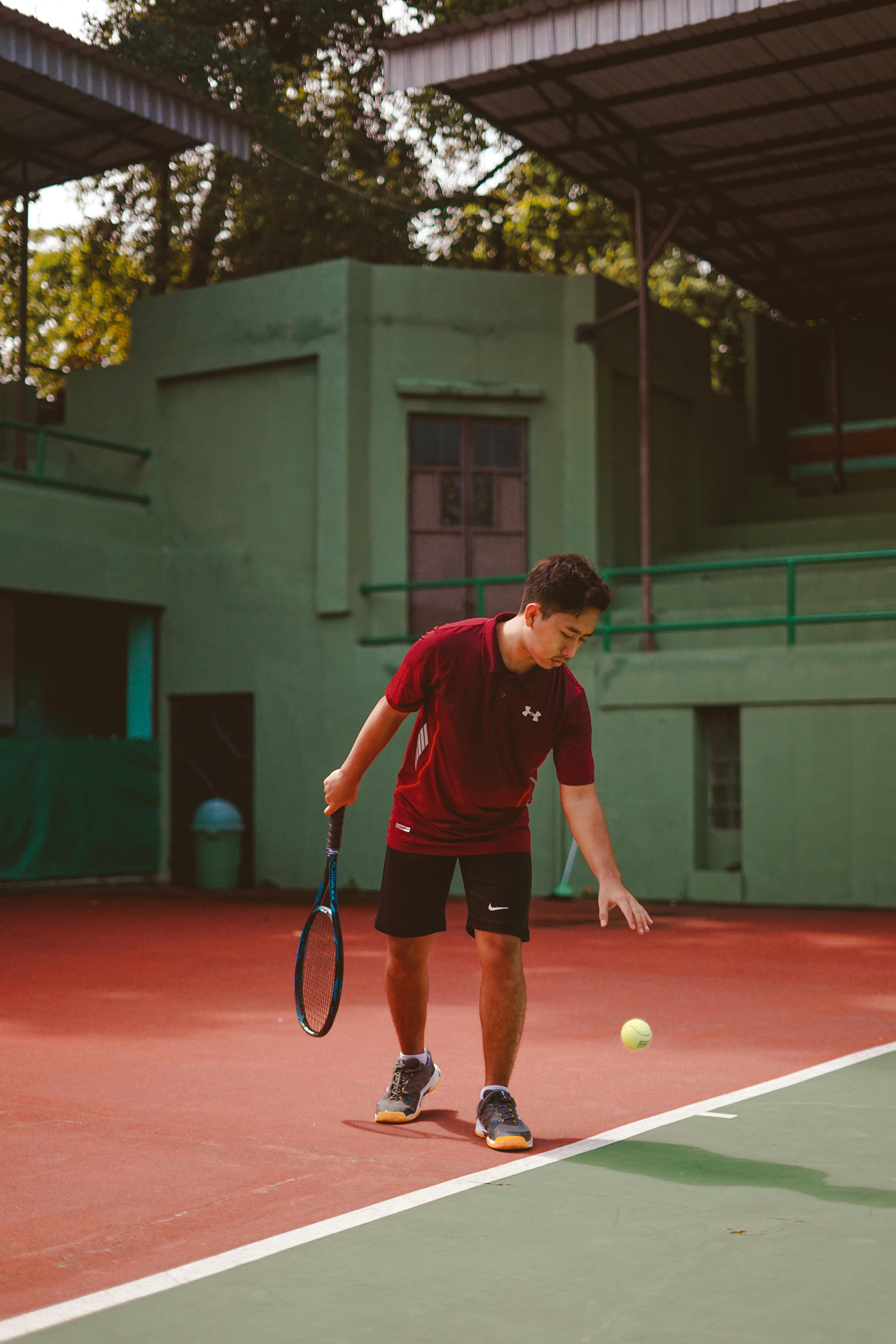 man in black short and red polo shirt playing tennis