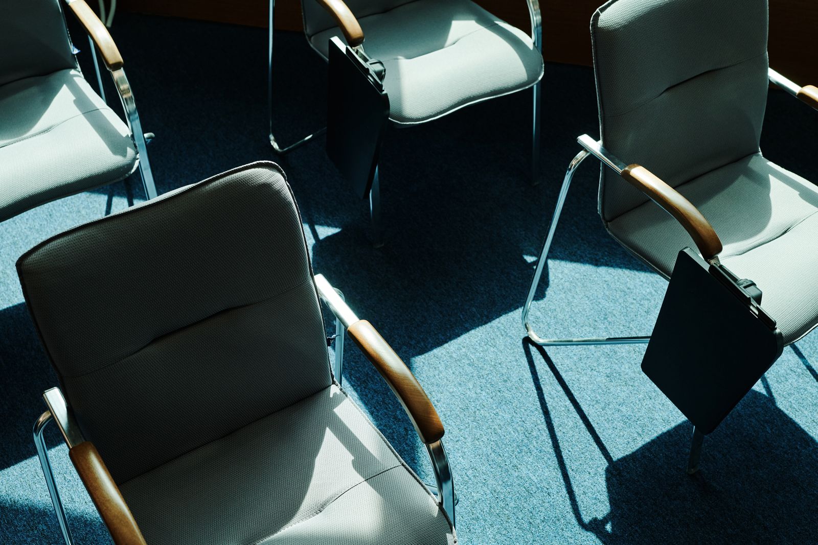 Overhead view of empty chairs around a sunlit meeting room table
