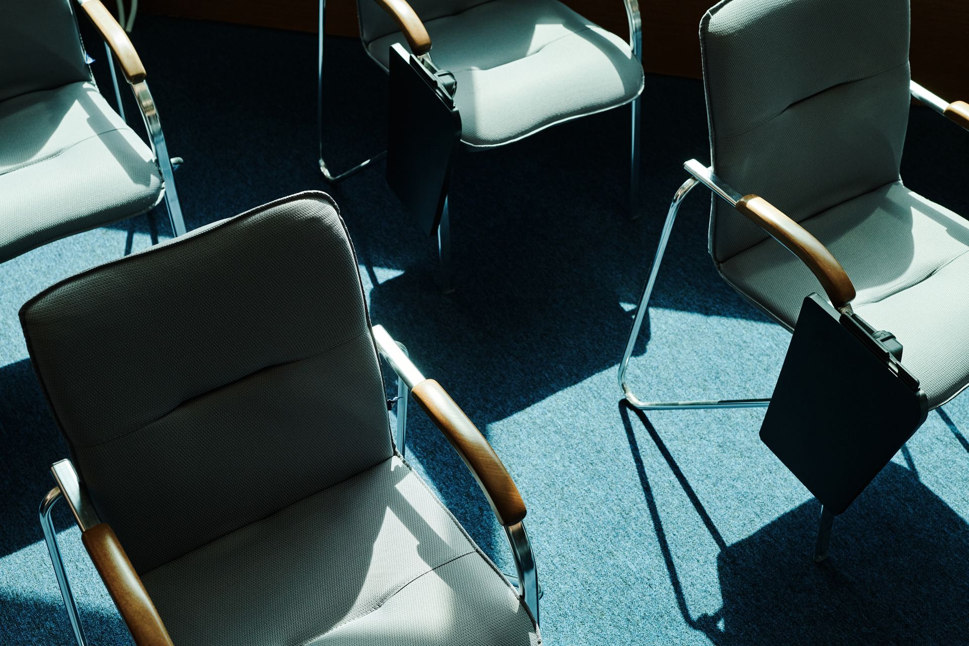 A view from above of empty chairs casting shadows in a sunlit office meeting room.