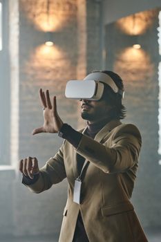 An adult man in a beige suit using VR goggles indoors, interacting with virtual interface.