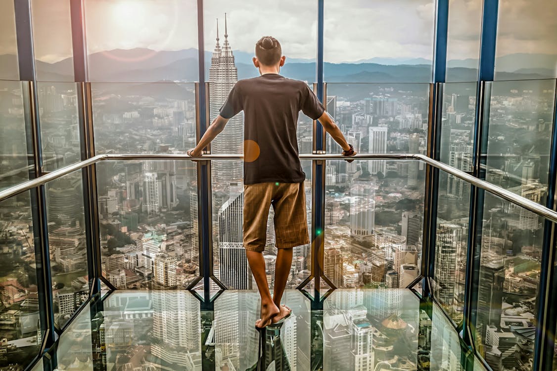 Free Man in Black T-shirt Looking Out of Glass Windows during Sunset Stock Photo