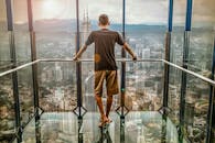一名男子赤脚站在吉隆坡高处的玻璃甲板上，欣赏着令人惊叹的城市景观