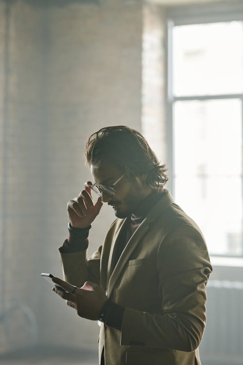 A Man in Brown Suit Using His Mobile Phone