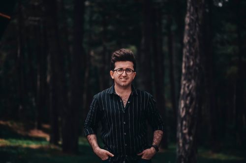 Free Portrait of a smiling man in glasses and striped shirt standing in a forest. Stock Photo
