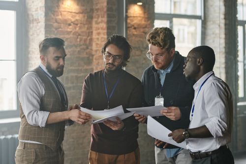 Free A diverse group of business professionals reviewing documents during a meeting in an industrial-style office space. Stock Photo