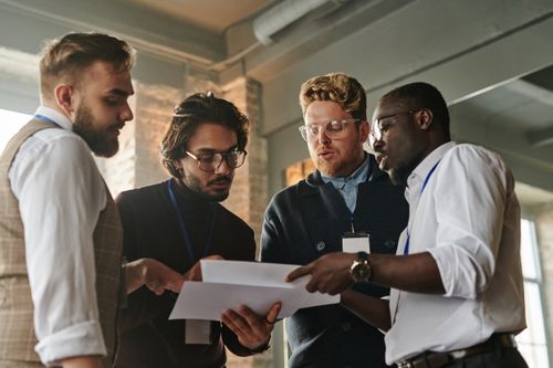 Free Four professionals engaged in a collaborative meeting, examining documents in an office. Stock Photo