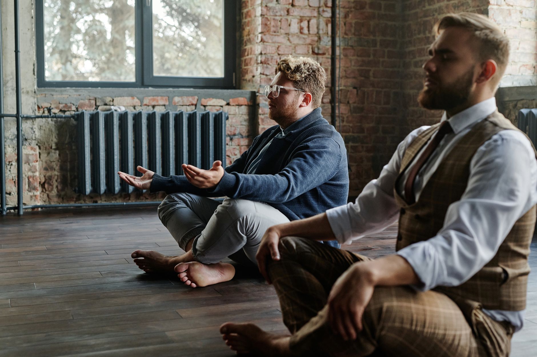 Two men meditating quietly in a rustic indoor setting, promoting mindfulness and relaxation