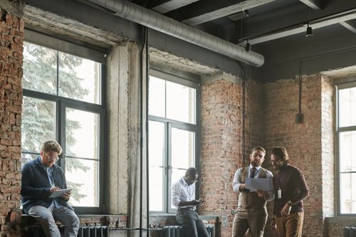 Free Casual business meeting in a loft-style office with a diverse team sharing ideas. Stock Photo