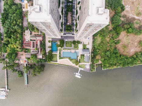 Drone shot of high-rise buildings along a lush, green waterfront.