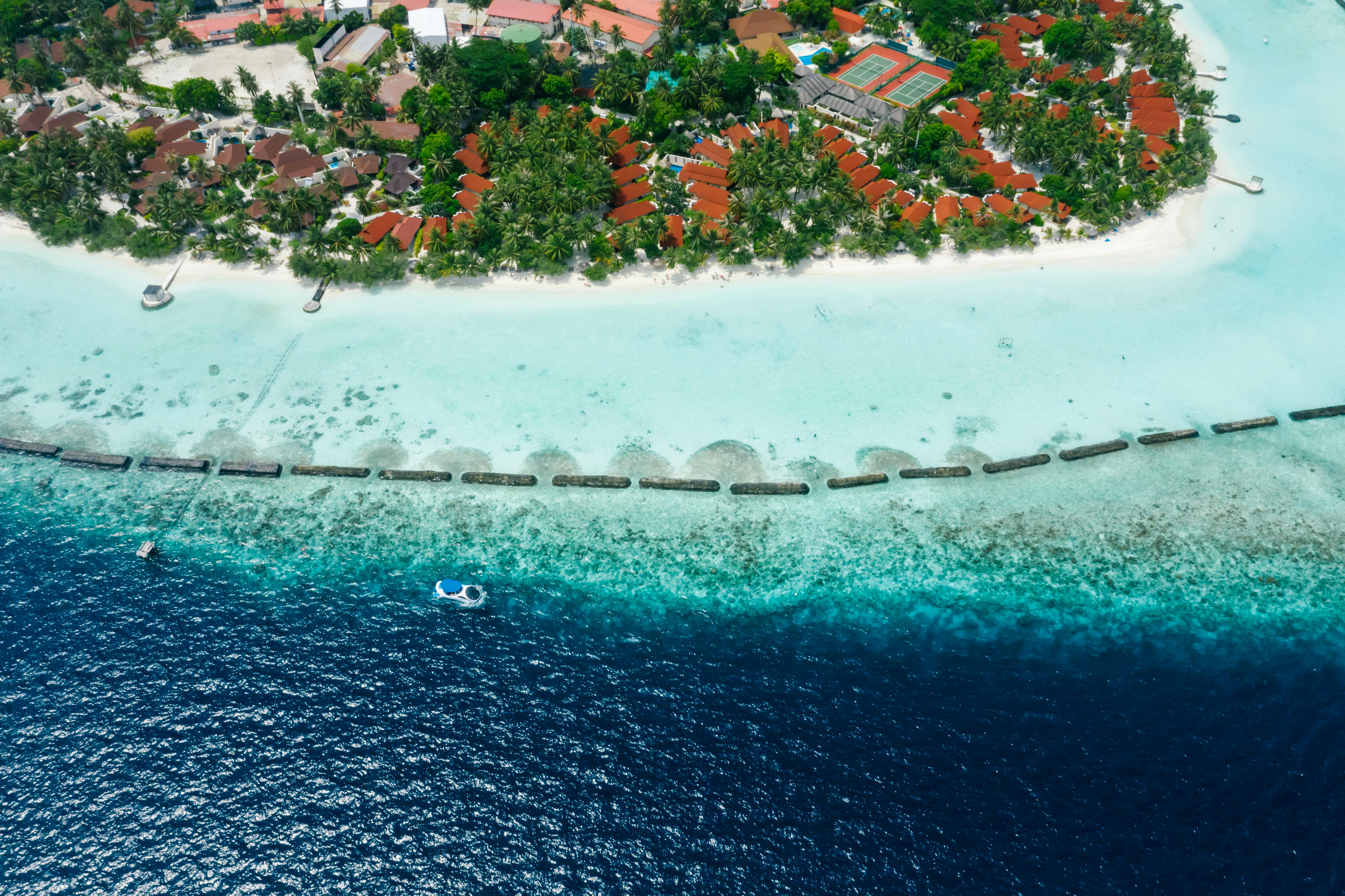 Stunning aerial view of a tropical island resort with turquoise waters and sandy beach.