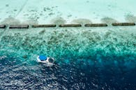 鸟瞰一艘小船在珊瑚礁上方清澈碧绿的海水中航行