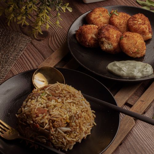 Free Delicious plate of fried rice served with crispy chicken croquettes on a dark wooden table. Stock Photo