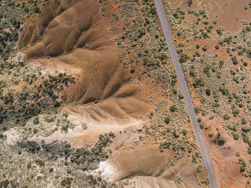 Free A stunning aerial view showcasing a desert road running through arid, rocky hills, emphasizing nature's raw beauty. Stock Photo
