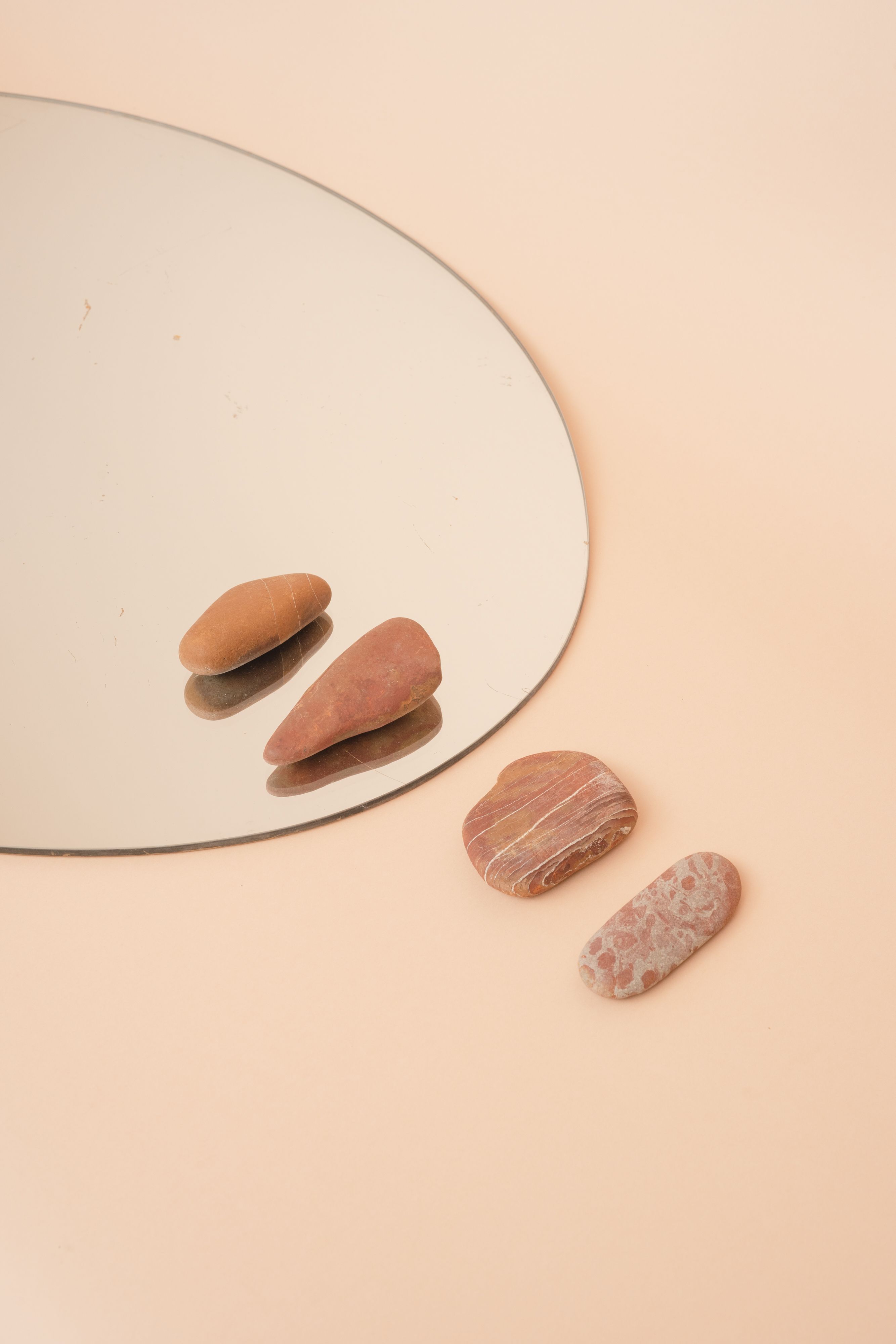 Minimalist composition of stones and mirror on a beige background.