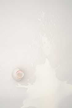 White surface with a spilled milk bottle, top view concept image.