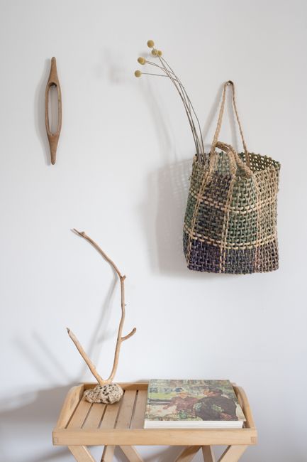 A minimalist interior decor setting featuring a wicker basket and natural elements on a wooden table.