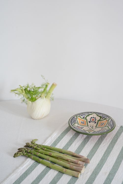Free Aesthetic still life of asparagus and fennel on a striped tablecloth with a patterned plate, perfect for food blogs. Stock Photo