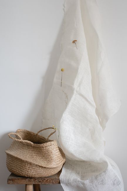 Elegant minimalist composition featuring a wicker basket and white draped fabric with subtle floral accents.