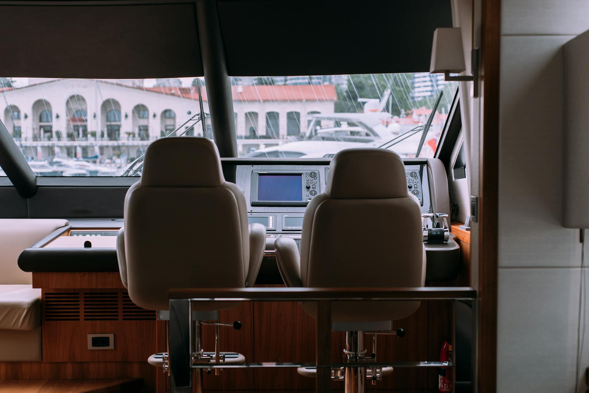 Sophisticated yacht interior showcasing a modern cockpit with leather seats and large windows overlooking a marina.