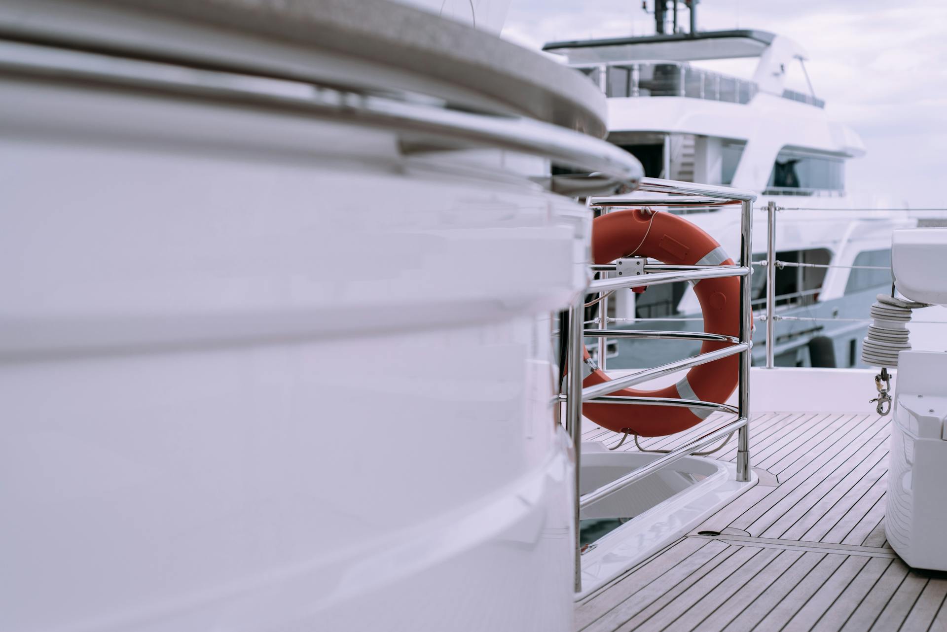 Close-up view of a yacht deck featuring a hanging lifebuoy and metal railings, showcasing maritime safety.