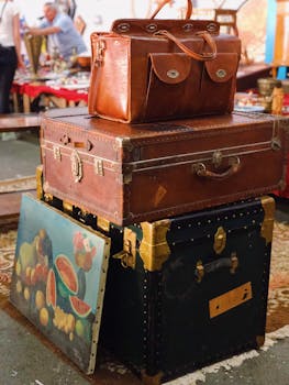 A collection of vintage leather bags and suitcases displayed outdoors at a public market.