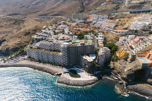 Free Scenic aerial view of a coastal resort in Gran Canaria with mountainous backdrop. Stock Photo