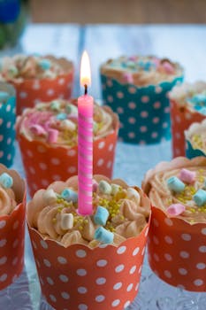 Vibrant polka dot cupcakes with a lit candle perfect for birthdays and celebrations.