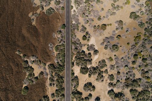Free Drone shot capturing a highway bisecting an arid landscape with sparse vegetation. Stock Photo