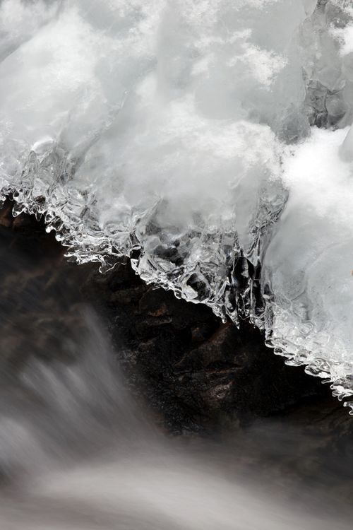 Free Close-up of a frozen stream with ice formations and flowing water, showcasing winter beauty. Stock Photo