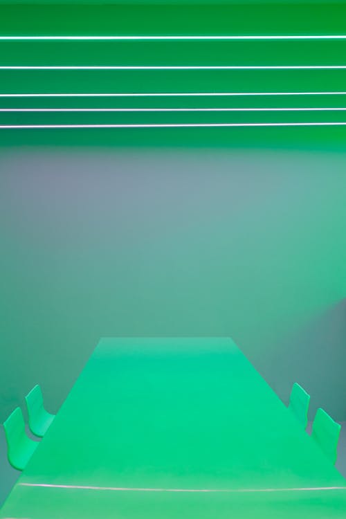 Empty Green Chairs and Table beside a Green Wall