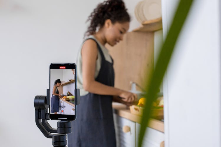 Woman While Cooking Being Recorded With Smartphone On Stabilizer 