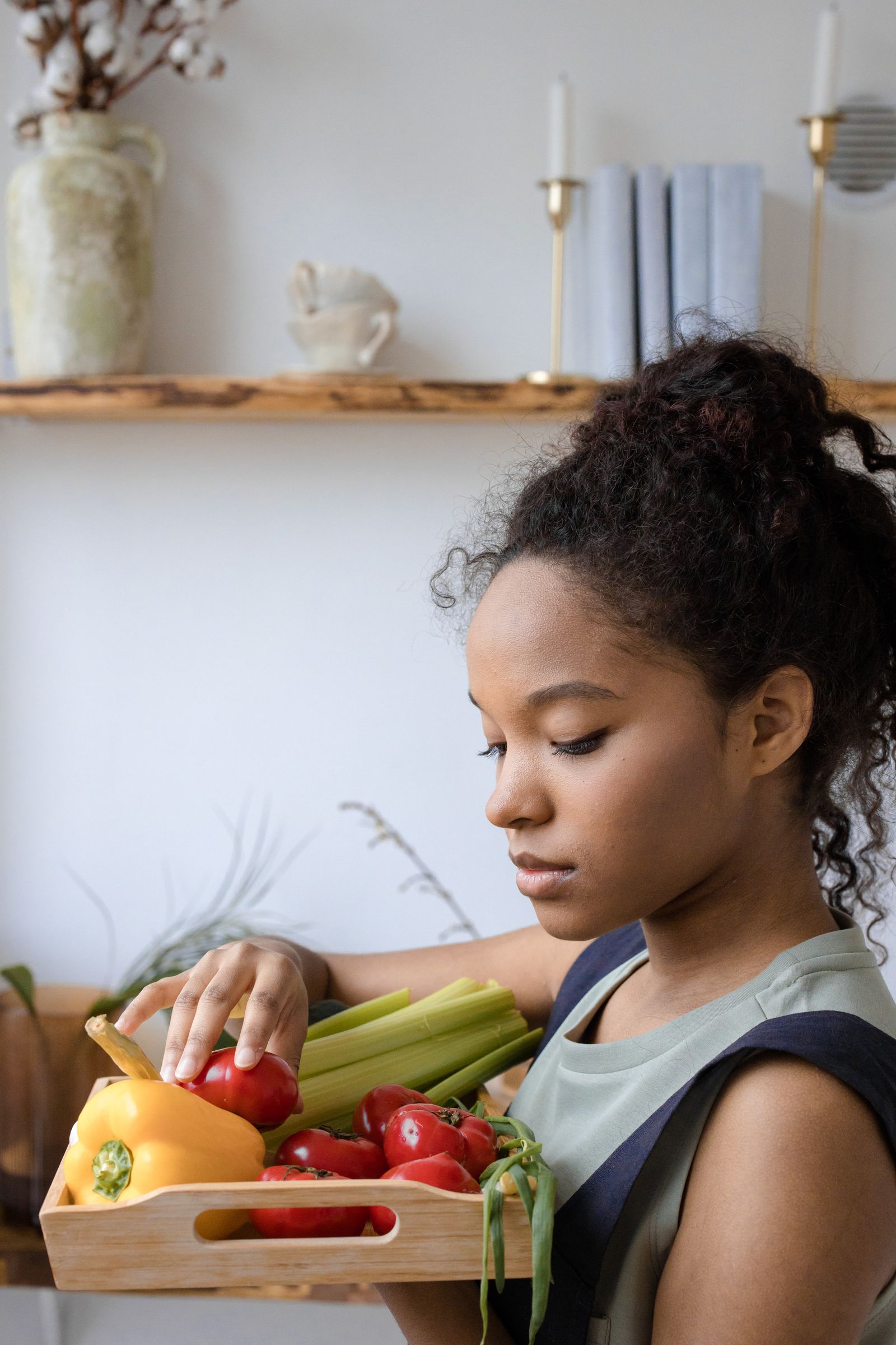 A Black woman holds a tray of fresh vegetables in her kitchen. Everyday food and movement choices can reverse prediabetes before it becomes diabetes.