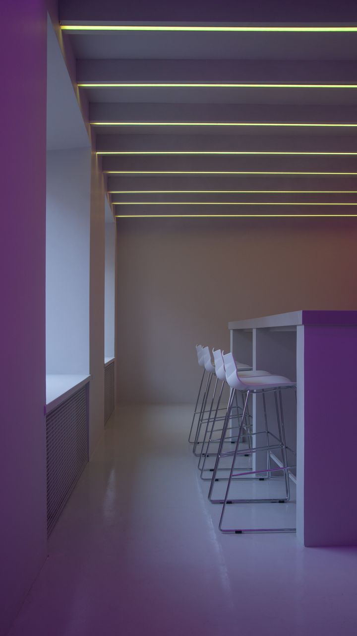 Warm recessed LED light strips under open shelves in a cozy office coffee bar nook
