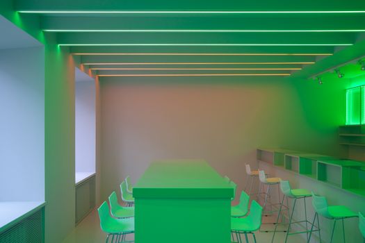 A contemporary room with minimalist design features unique neon green lighting and sleek furniture.