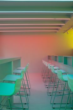 Brightly lit minimalist interior featuring neon lights and sleek bar stools.