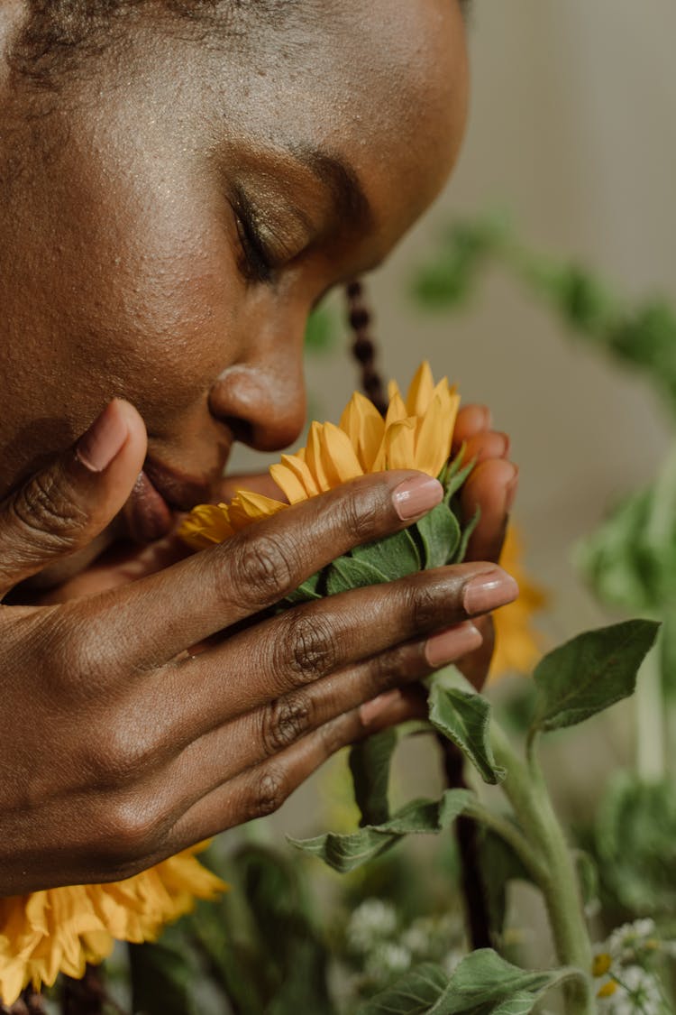 Close-Up Photo Of A Woman Smelling A Yellow Flower