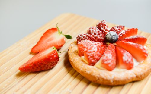 Free A delightful strawberry tart with fresh cream and powdered sugar served on a wooden board. Stock Photo