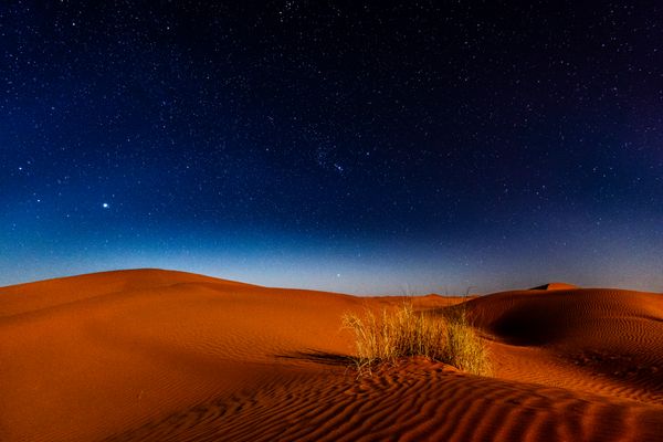 Night sky over desert sand dunes — photo by Sergey Pesterev on Pexels