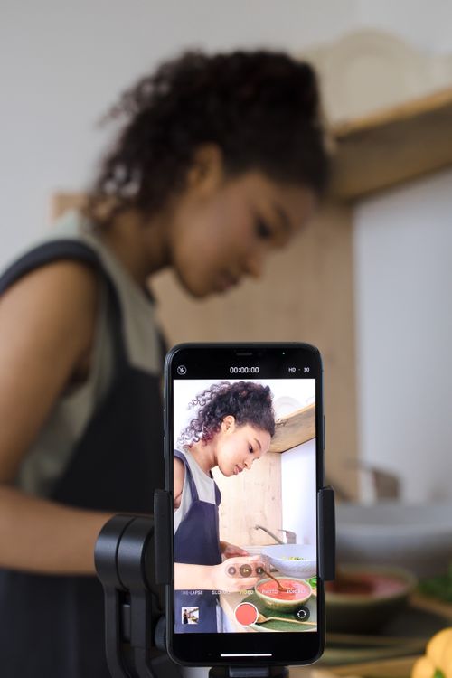 Free A woman records a cooking video using a smartphone, focusing on preparing a meal. Stock Photo