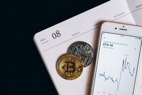 Free A smartphone displays cryptocurrency data alongside Bitcoin and Ethereum coins on an August calendar. Stock Photo