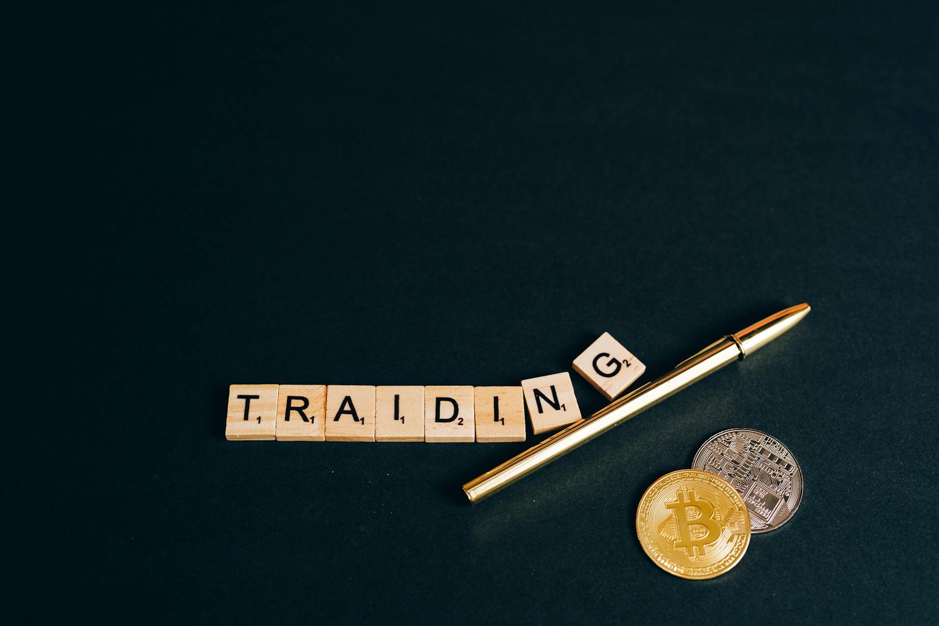Bitcoin and trading concept shown with coins, pen, and letter tiles on a dark background.