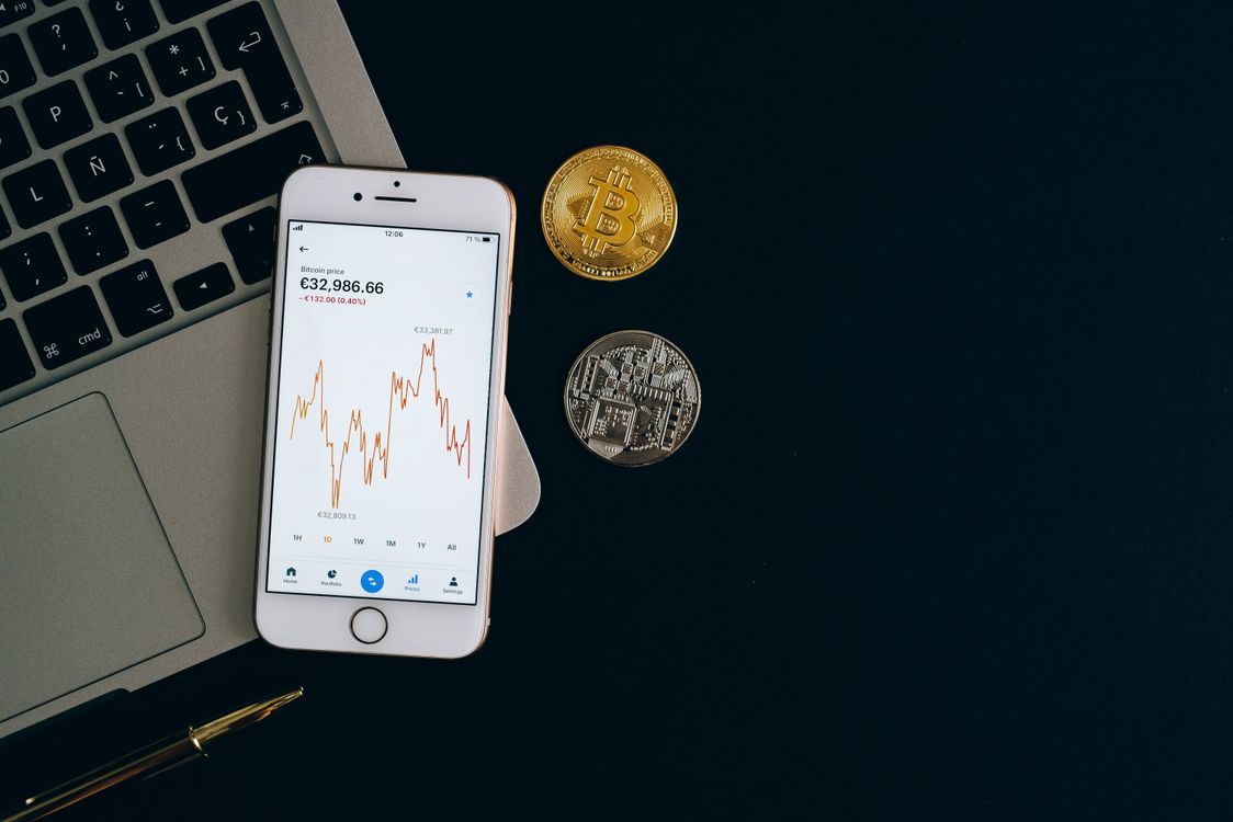 Pametni telefon s prikazanom cijenom Bitcoina i Ethereuma s fizičkim kovanicama
