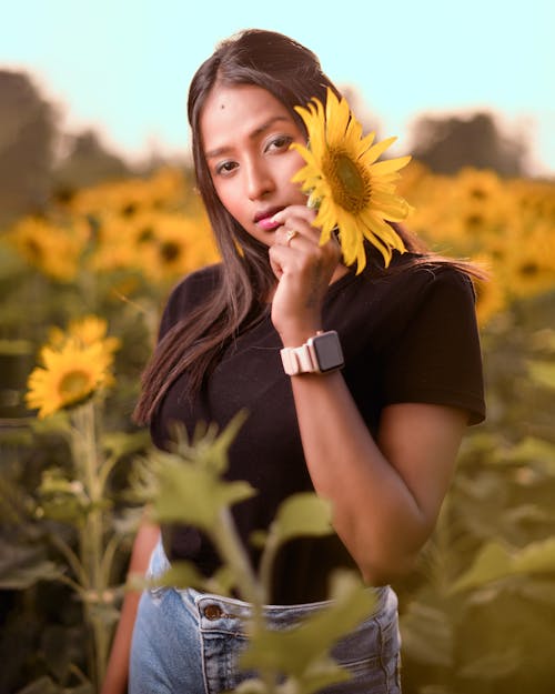 Woman in Black Shirt Holding a Sunflower