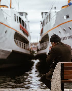 A man seated on a bench overlooking the sea and docked ships in Istanbul.